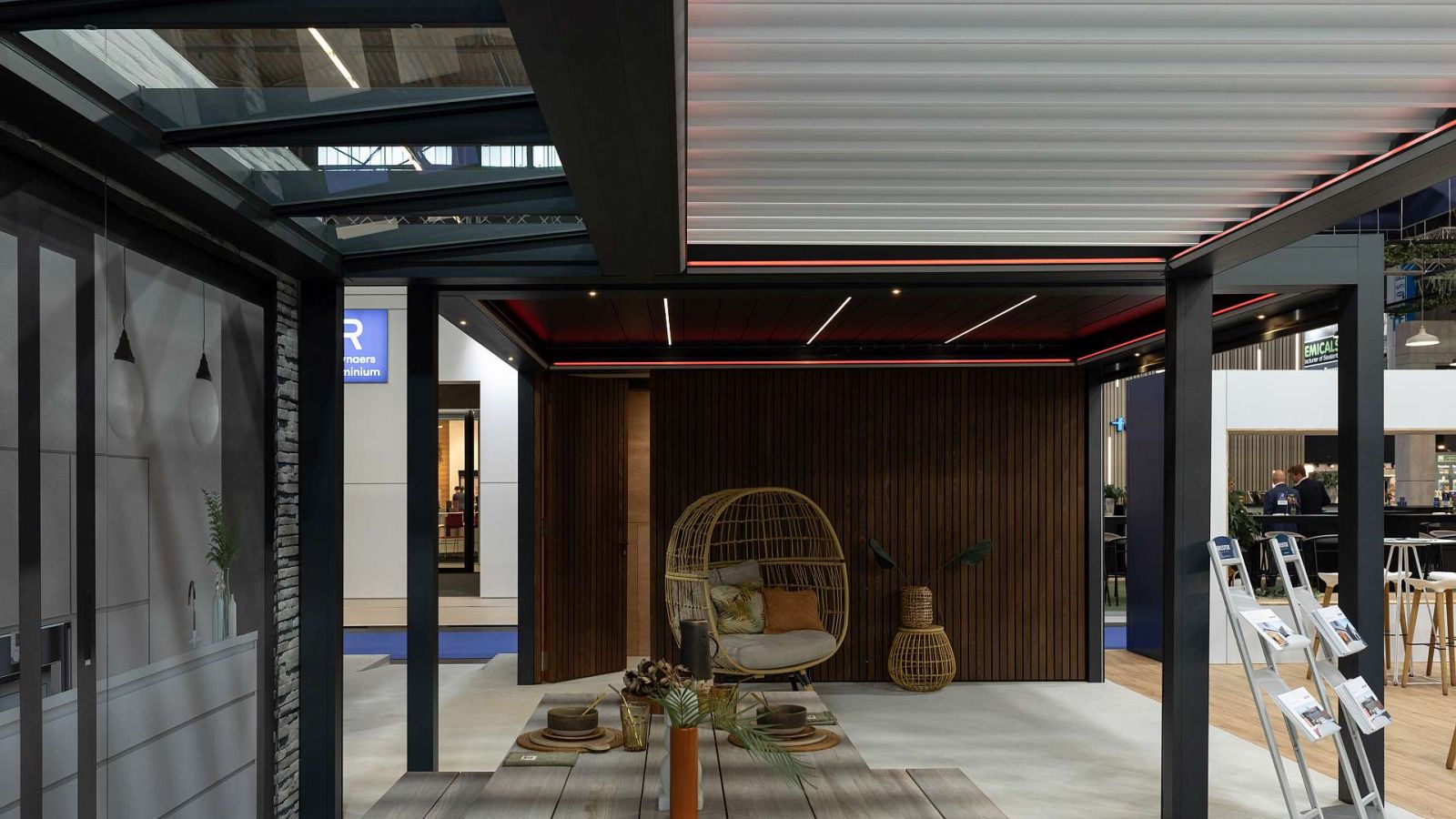 Ein Glasdach mit Lamellen mit dunkler Holzwand im Hintergrund.