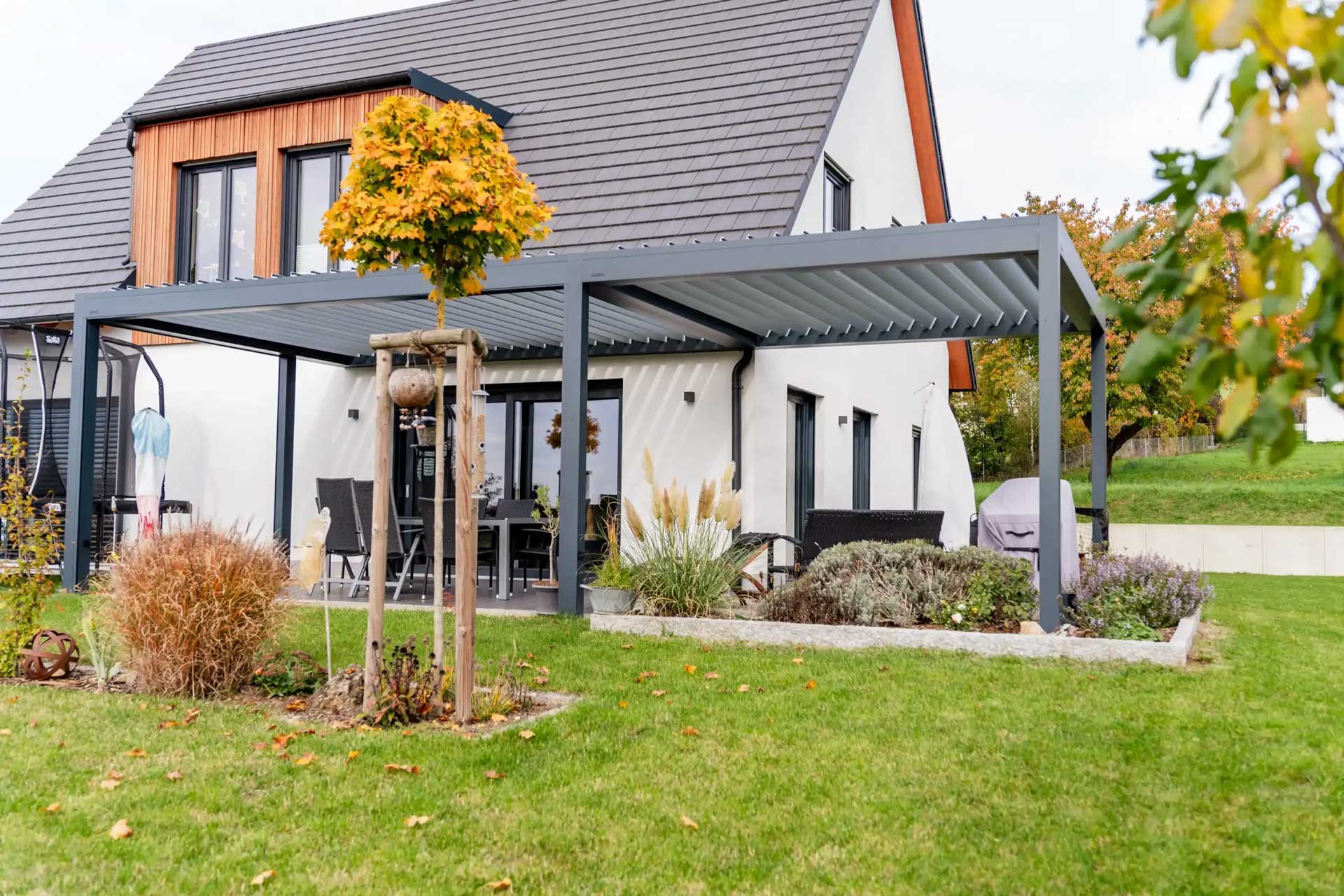 Die Terrassenüberdachung in Amberg in dunkel grauer Farbe an einem Einfamilienhaus mit Garten.