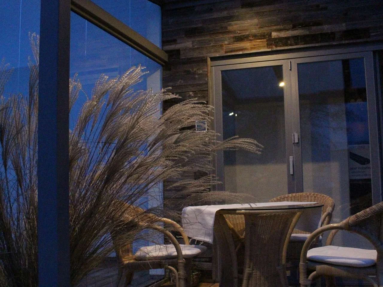 Eine bei Nacht mit LED beleuchtete Terrassenüberdachung mit Sitzgruppe.