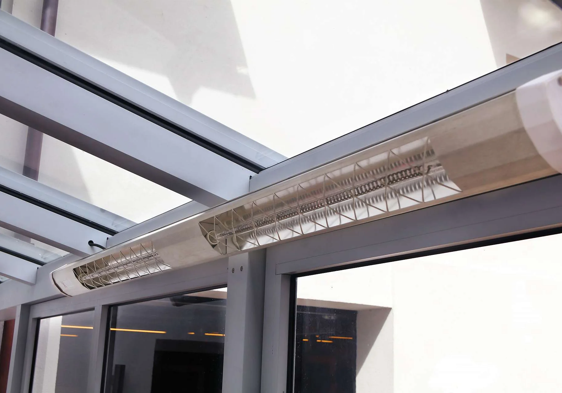 Eine etwa zwei Meter große Infrarotheizung an der Querstrebe der Terrassenüberdachung befestigt.