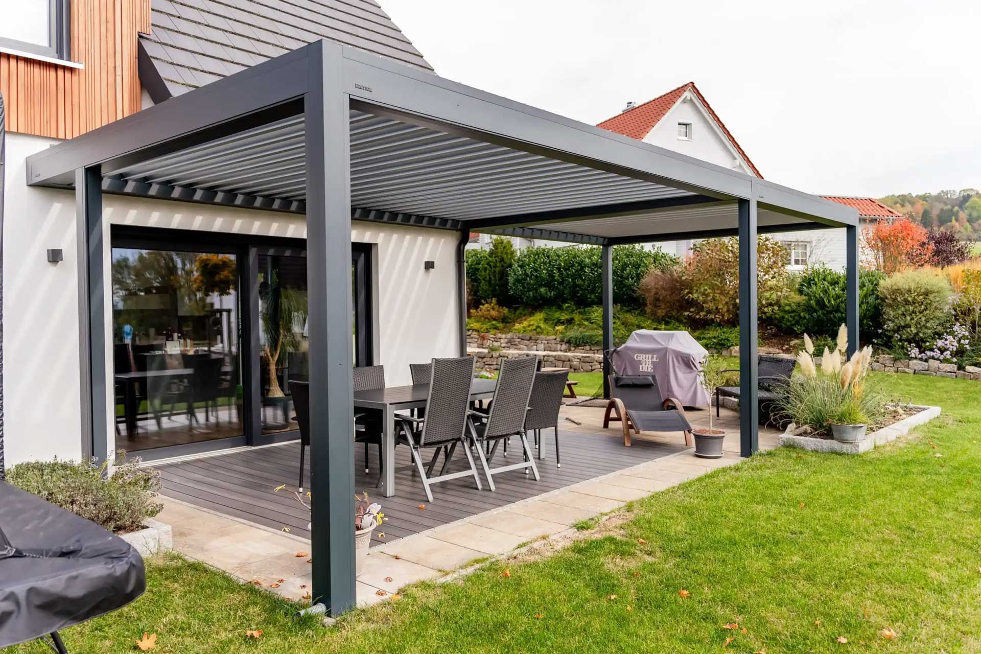 Die Terrasenüberdachung Ansbach in dunkel grauer Ausführung. Im Hintergrund sieht man das Nachbarhaus.